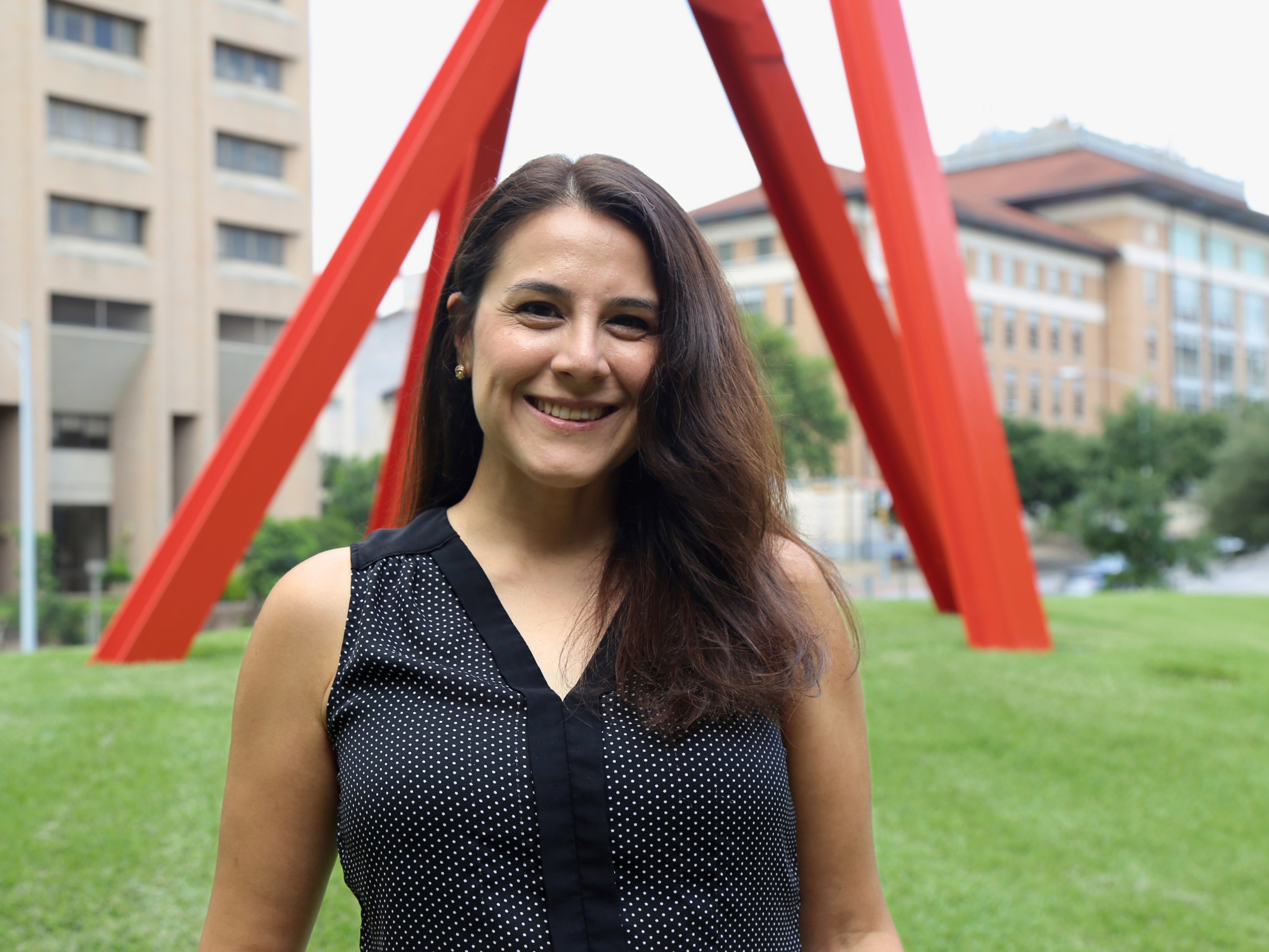 Melany Davis smiles in front of The Clock Knot at UT Austin
